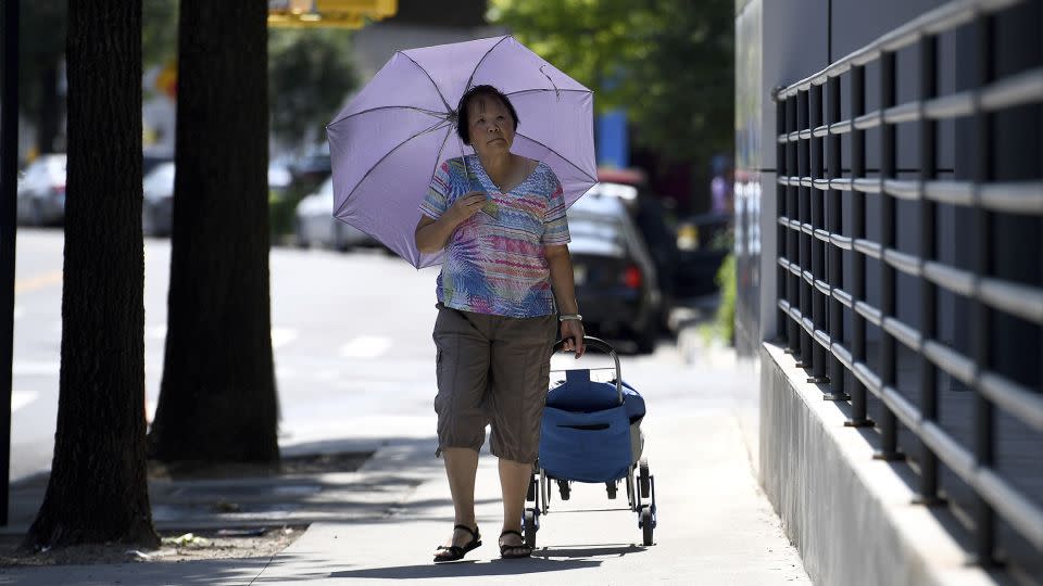 A woman uses an umbrella to shade herself from the sun in the Queens borough of New York City, NY, June 18, 2024. The city is under an extreme heat alert. - Anthony Behar/SIPPL Sipa USA/AP