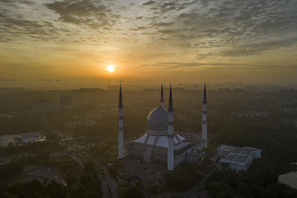 The sun rises behind the Sultan Salahuddin Abdul Aziz Mosque in Shah Alam on the outskirts of Kuala Lumpur, Malaysia, Sunday, July 16, 2023. (AP Photo/Vincent Thian)