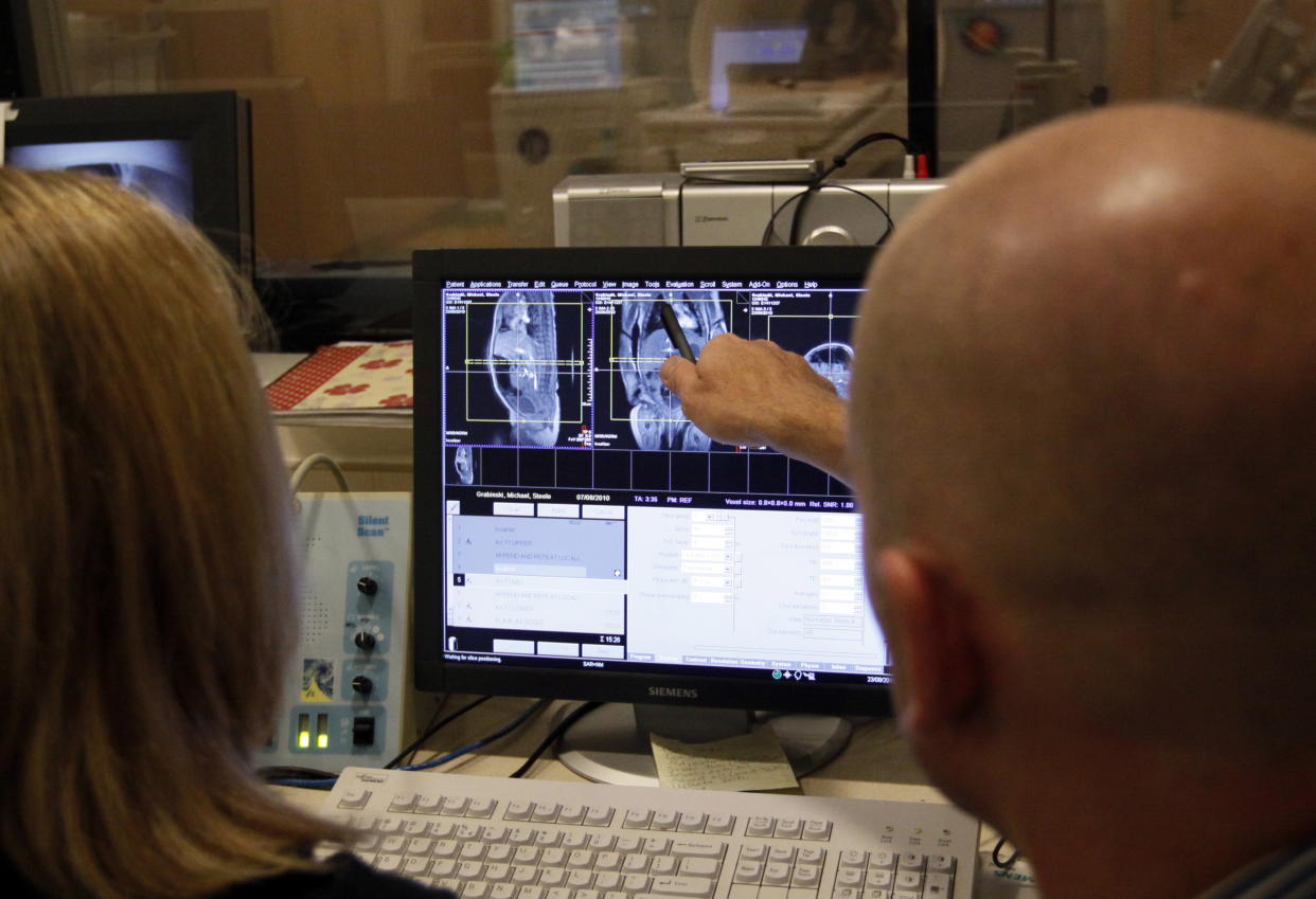 Dr. David Brumbaugh (R) and Claire Skold, MRI Technologist looks at live MRI images of Michael Grabinski, (background) two weeks old at The Children's Hospital in Aurora, Colorado August 23, 2010 during a research study on obesity in infants. The overall theme of the study is to understand the continuum of growth that starts really at conception, and to understand if the earliest phases of growth impacts later risk for obesity.   REUTERS/Rick Wilking (UNITED STATES)