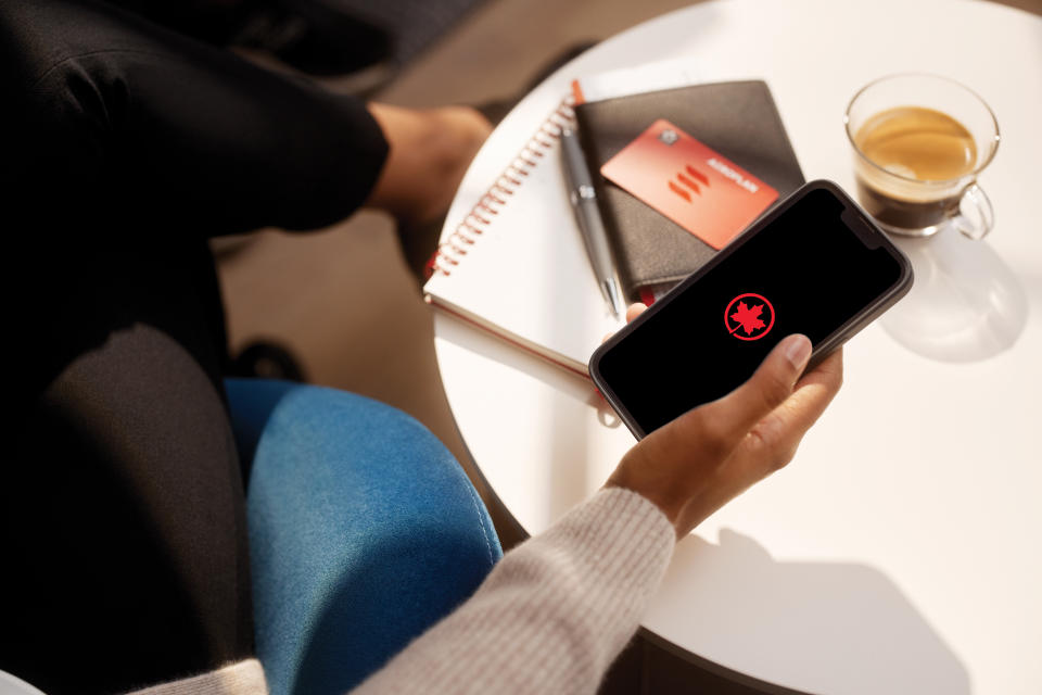 A shot of a woman looking at the Aeroplan app on her phone as she looks to maximize her travel budget and vacation dollars