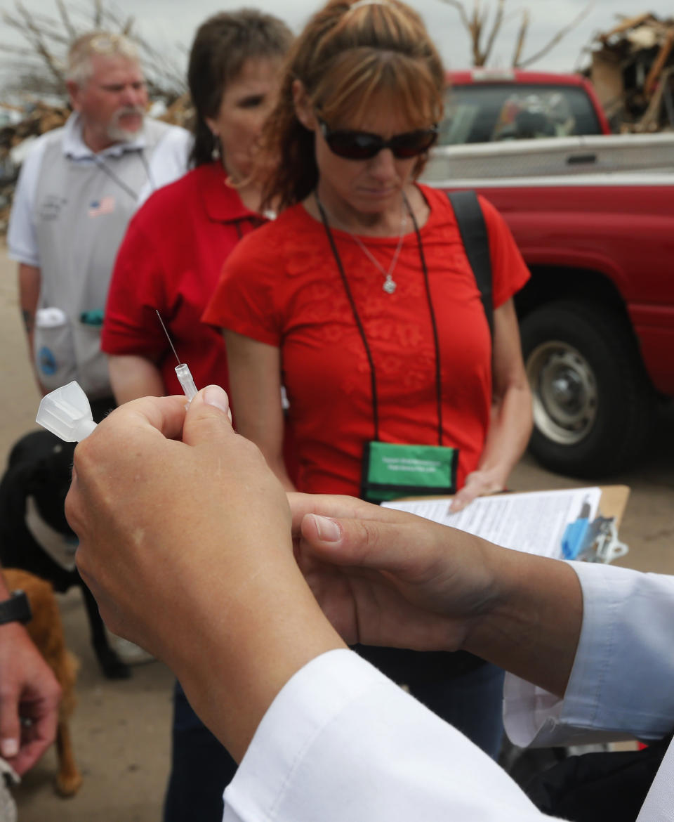 FILE - In this May 27, 2013 file photo a needle with tetanus vaccine is prepared by a nurse practitioner on a tornado ravaged street in Moore, Okla. An unvaccinated 6-year-old Oregon boy was hospitalized for two months for tetanus and almost died of the bacterial illness after getting a deep laceration on his forehead while playing on a farm, according to a case study published Friday, March 8, 2019 by the U.S. Centers for Disease Control and Prevention. (AP Photo/Sue Ogrocki,File)