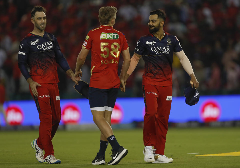 Royal Challengers Bangalore's Virat Kohli, right, shakes hands with Punjab Kings Sam Curran, center, as Glenn Maxwell watches during the Indian Premier League cricket match in Mohali, India, Thursday, April 20, 2023. (AP Photo/Surjeet Yadav)