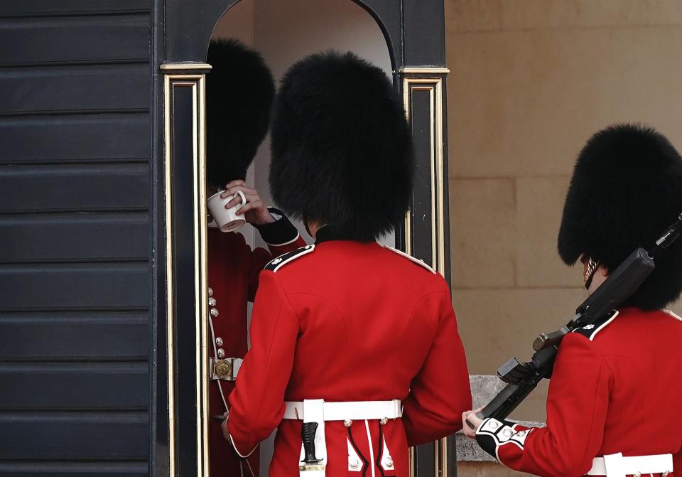 Soldiers from the Queen's Guard deliver a drink to their colleagues on the forecourt of Buckingham Palace. Picture date: Monday July 18, 2022.