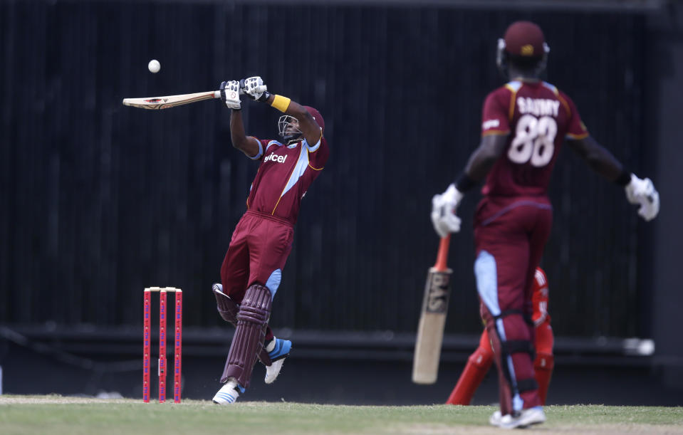 West Indies' Dwayne Bravo plays a shot for four runs of England's Chris Jordan as Darren Sammy looks on during their first one-day international cricket match at the Sir Vivian Richards Cricket Ground in St. John's, Antigua, Friday, Feb. 28, 2014. (AP Photo/Ricardo Mazalan)