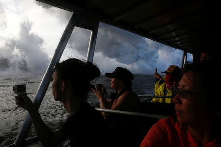People watch as lava flows into the Pacific Ocean southeast of Pahoa during ongoing eruptions of the Kilauea Volcano in Hawaii, U.S., May 20, 2018. REUTERS/Terray Sylvester