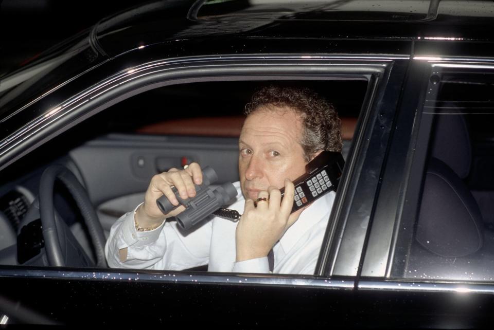 anthony pellicano holding a phone and binoculars inside his car