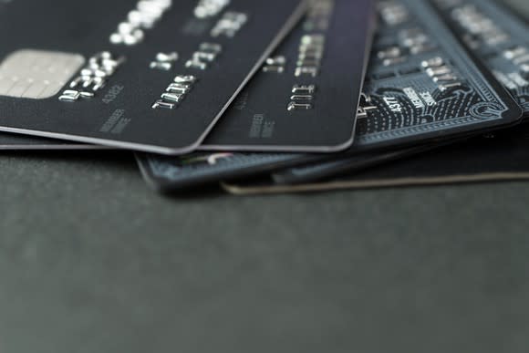 Five credit cards fanned out on a dark table.