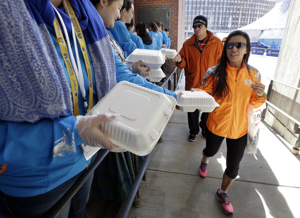 Runners and guests receive containers for their Boston Marathon pre-race dinner at Boston City Hall, Sunday, April 20, 2014, in Boston. With an expanded field of runners and the memory of last year's bombings the 2014 Boston Marathon could bring an unprecedented wave of visitors to the area. (AP Photo/Steven Senne)