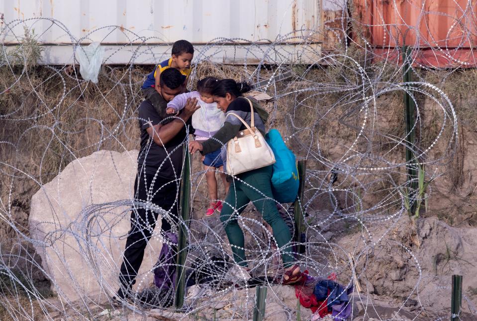 Migrants breach a section of concertina wire after crossing the Rio Grande on July 20 from Piedras Negras, Coahuila, Mexico into Eagle Pass, Texas, hoping to be granted asylum in the United States.