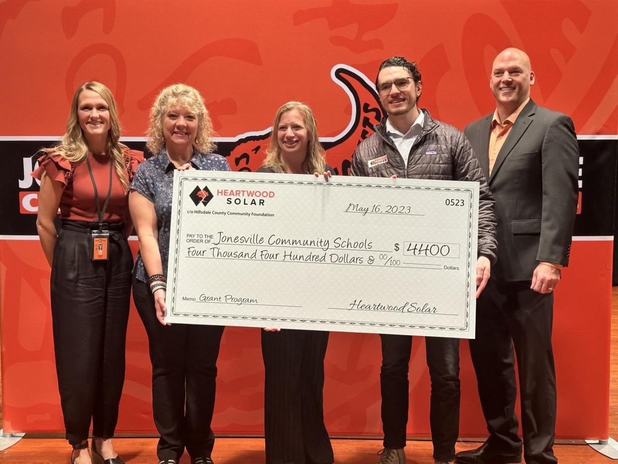 From left, Jonesville High School Principal Katie Griffiths, teachers Michelle VandyBogurt and Andrea McKelvey, Toby Valentino of Ranger Power, and Jonesville Community Schools Superintendent Erik Weatherwax pose for a photo with a ceremonial check representing a $4,400 contribution from Heartwood Solar to the schools.