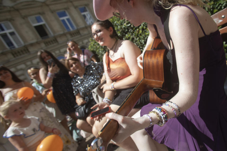 Several people near a woman holding a guitar.