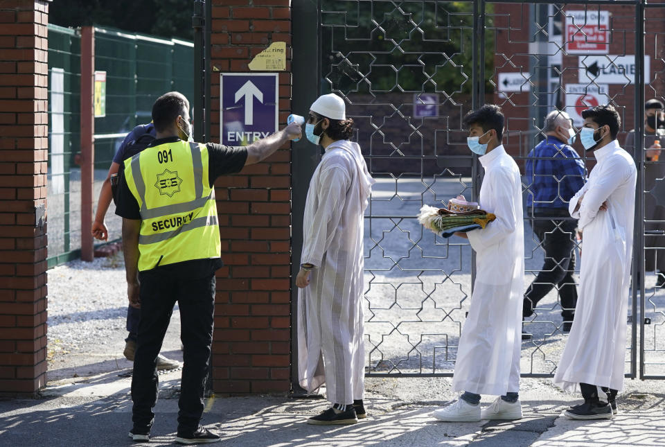 FILE - In this file photo dated Friday, July 31, 2020, people wearing face masks have their temperatures checked before being allowed to go into Manchester Central Mosque, as Muslims worldwide marked the start of the Eid al-Adha holiday, in Manchester, northern England. The British government insists that science is guiding its decisions as the country navigates its way through the coronavirus pandemic. But a self-appointed group of independent experts led by a former government chief adviser says it sees little evidence-based about Britain’s response. Unlike other countries, the scientific opposition to Britain’s approach is remarkably organized. The independent group sits almost in parallel to the government’s own scientists, assesses the same outbreak indicators and has put out detailed reports on issues such contact tracing, reopening schools and pubs, and relaxing social distancing(AP Photo/Jon Super, File)