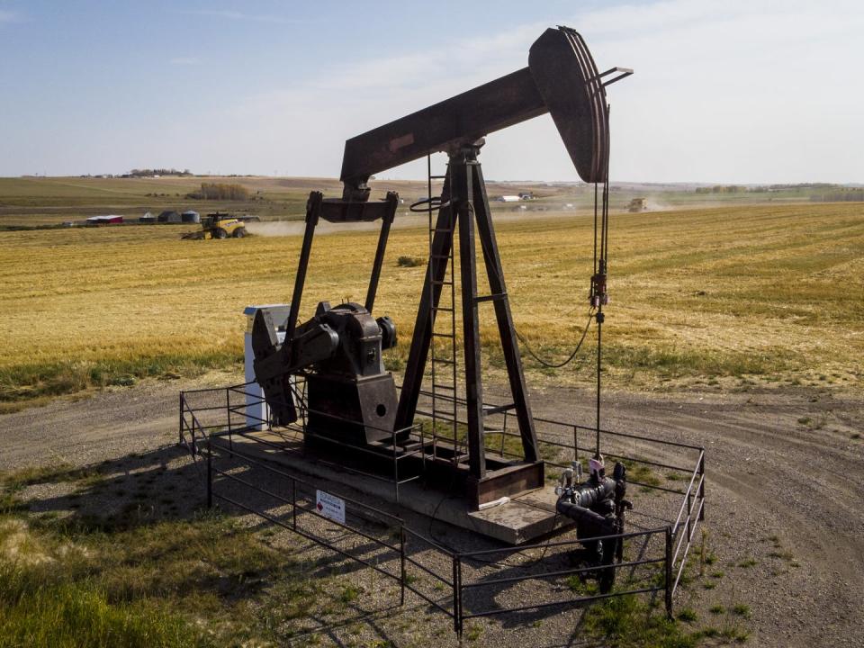 A pumpjack is seen surrounded by a golden wheat field.