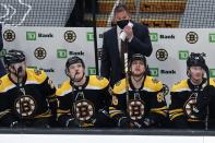 Boston Bruins head coach Bruce Cassidy stands behind his team as they look up at the scoreboard after a goal by Washington Capitals' Conor Sheary during the second period of an NHL hockey game, Sunday, April 11, 2021, in Boston. (AP Photo/Michael Dwyer)