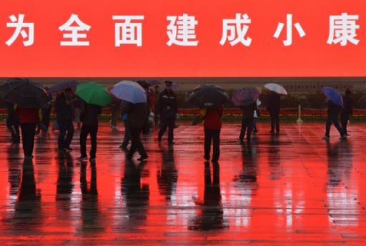 A policeman (centre) keeps watch over Chinese tourists as they walk in Tiananmen Square. The Chinese Communist Party's paranoia is on full display for its congress in Beijing in a security squeeze extending from police swarming Tiananmen Square to elderly sentinels watching street corners