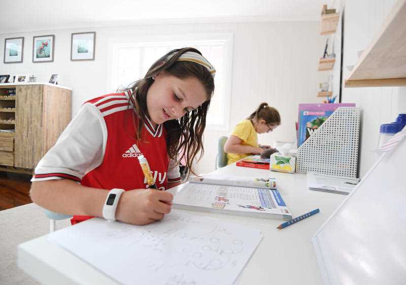 Audrey Merriman (left), 9, and her sister Grace, 8, are seen learning from home on the first day of Term 2 in Brisbane.