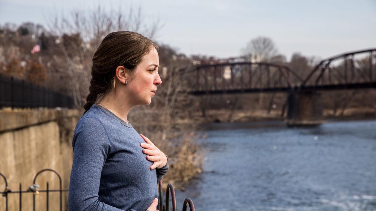 a runner taking a deep breath by a river