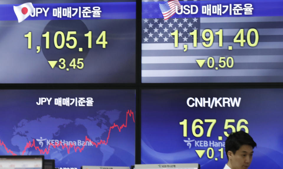 A currency trader walks by the screens showing the foreign exchange rates at the foreign exchange dealing room in Seoul, South Korea, Monday, Sept. 16, 2019. Asian stock markets were mixed Monday after crude prices surged following an attack on Saudi Arabia's biggest oil processing facility. (AP Photo/Lee Jin-man)