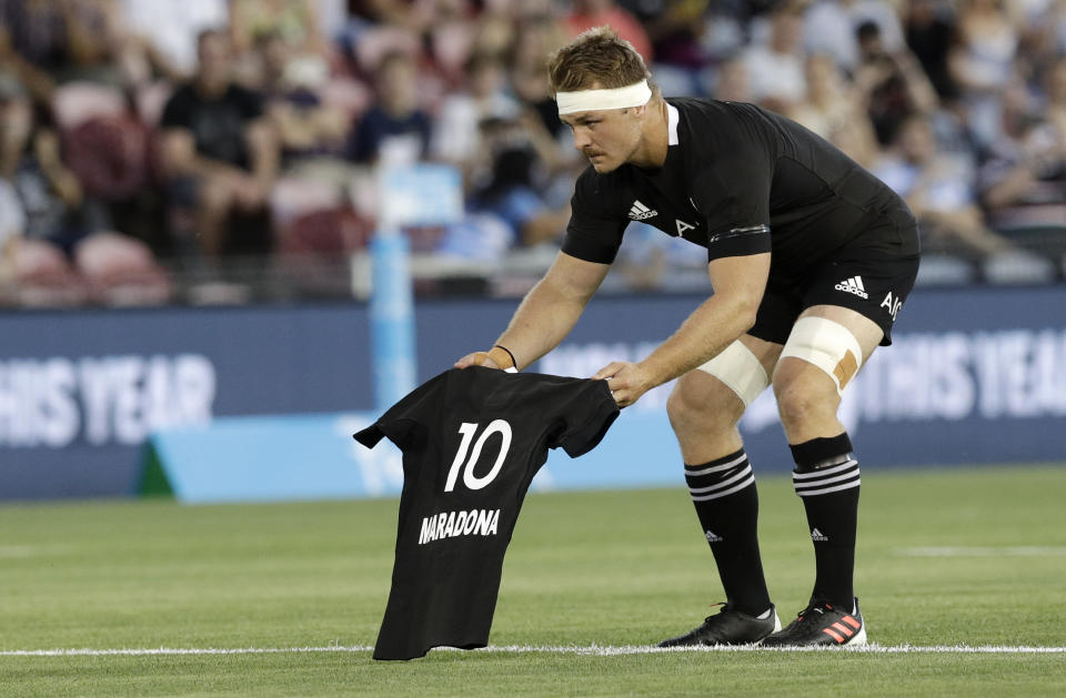 Sam Cane, de Nueva Zelanda, coloca un jersey con el número 10 y el apellido de Diego Maradona, antes del duelo del torneo de rugby de las Tres Naciones ante Argentina, el sábado 28 de noviembre de 2020, en Newcastle, Australia (AP Foto/Rick Rycroft)