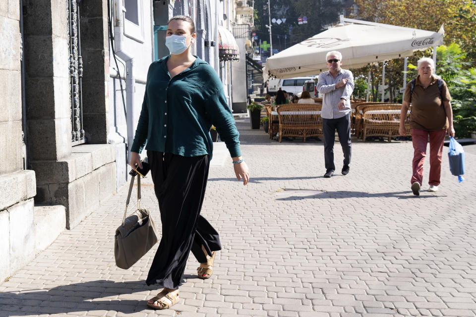 A woman wearing a face mask walks down a street in Kyiv, Ukraine, Friday Sept. 20, 2024 on a day with poor air quality. (AP Photo/Tony Hicks)