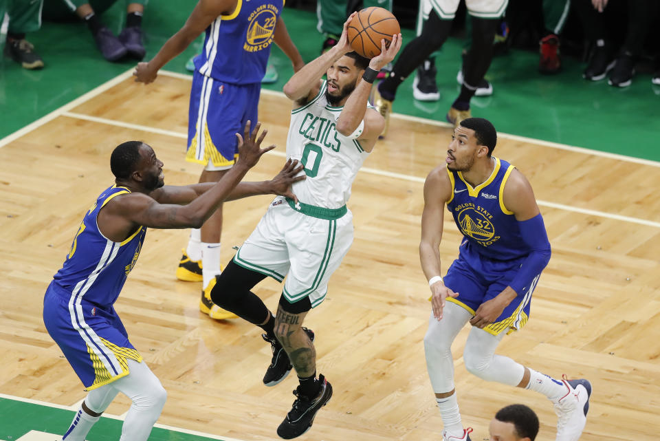 Boston Celtics forward Jayson Tatum (0) splits the defense of Golden State Warriors forward Draymond Green (23) and forward Otto Porter Jr. (32) during the first quarter of Game 6 of basketball's NBA Finals, Thursday, June 16, 2022, in Boston. (AP Photo/Michael Dwyer)