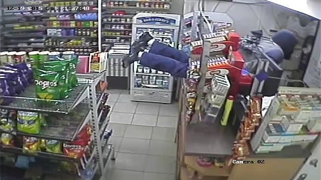 The armed attacker can be seen sliding along the convenience store counter and threatening the attendant. Photo: NSW Police