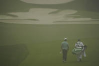 Hideki Matsuyama, of Japan, walks down a foggy 10th fairway with his caddie during the first round of the Masters golf tournament Thursday, Nov. 12, 2020, in Augusta, Ga. (AP Photo/Charlie Riedel)