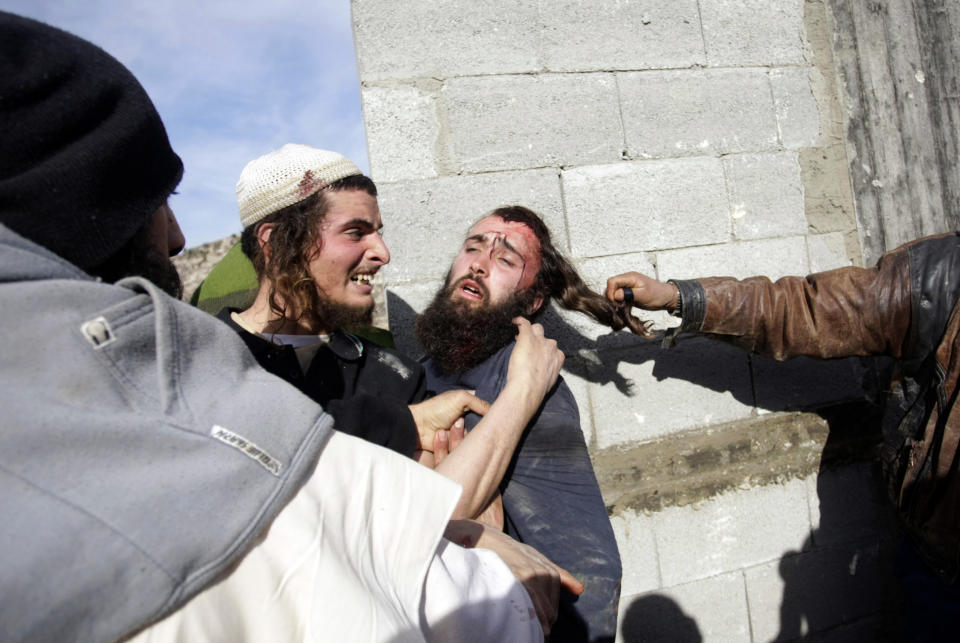 Palestinians hit injured Israeli settlers, center, detained by Palestinian villagers in a building under construction near the West Bank village of Qusra, southeast of the city of Nablus, Tuesday, Jan. 7, 2014. Palestinians held more than a dozen Israeli settlers for about two hours Tuesday in retaliation for the latest in a string of settler attacks on villages in the area, witnesses said. The military said the chain of events apparently began after Israeli authorities removed an illegally built structure in Esh Kodesh, a rogue Israeli settlement in the area. In recent years, militant settlers have often responded to any attempts by the Israeli military to remove parts of dozens of rogue settlements, or outposts, by attacking Palestinians and their property. The tactic, begun in 2008, is known as "price tag." (AP Photo/Nasser Ishtayeh)