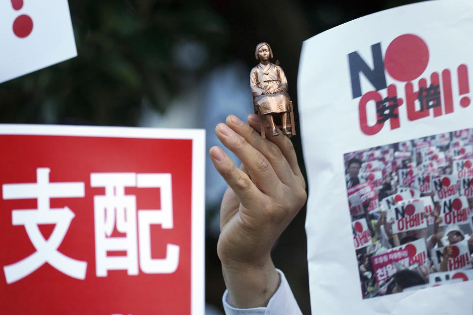 In this Aug. 8, 2019 photo, one of protesters holds a miniature model of a statue of a girl symbolizing the issue of wartime "comfort women" during a rally outside Japanese Prime Minister Shinzo Abe's residence in Tokyo. South Korea and Japan have locked themselves in a highly-public dispute over history and trade that in a span of weeks saw their relations sink to a low unseen in decades. (AP Photo/Eugene Hoshiko)