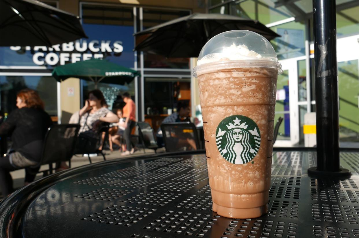 Coquitlam, BC, Canada - April 30, 2016 : One side of people drinking Starbucks coffee on sunny day.  Starbucks is the largest coffeehouse company in the world.