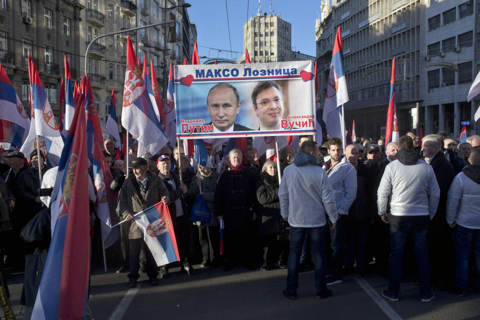 Supporters of Russia's president Vladimir Putin and his Serbian counterpart Aleksandar Vucic hold a banner depicting the two during a show of support in Belgrade, Serbia, Thursday, Jan. 17, 2019. Amid a lavish welcome, Putin arrived in Serbia on Thursday in a show of the Russian president's support for the Balkan country's populist leader and his pro-Moscow policies. (AP Photo/Marko Drobnjakovic)