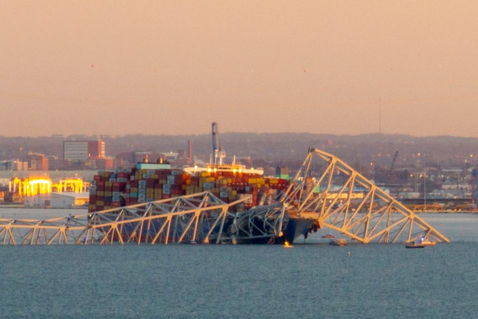 The steel frame of the Francis Scott Key Bridge sits on top of a container ship after it struck the bridge in Baltimore, Maryland, on March 26, 2024.