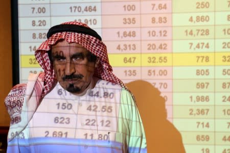 Saudi man stands in front of a screen showing stock prices at ANB Bank in Riyadh
