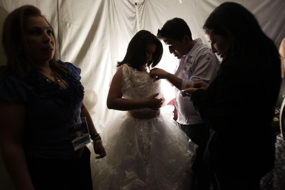 In this Feb, 5, 2013 photo, Cintia Caraguay, is helped with a dress as she prepares to model a creation before the start of the Bionic Fashion show backstage at the Metropolitan Cultural Center in Quito, Ecuador. Caraguay, a cancer survivor from Ecuador whose right leg was amputated to to cancer, joined 15 other models from Argentina, Brazil, Bolivia, Costa Rica, Colombia and Venezuela to model creations by Ecuadorian designers at an event organized by the Youth Against Cancer Foundation which aimed to break stereotypes and social barriers for the young cancer survivors. (AP Photo/Dolores Ochoa)