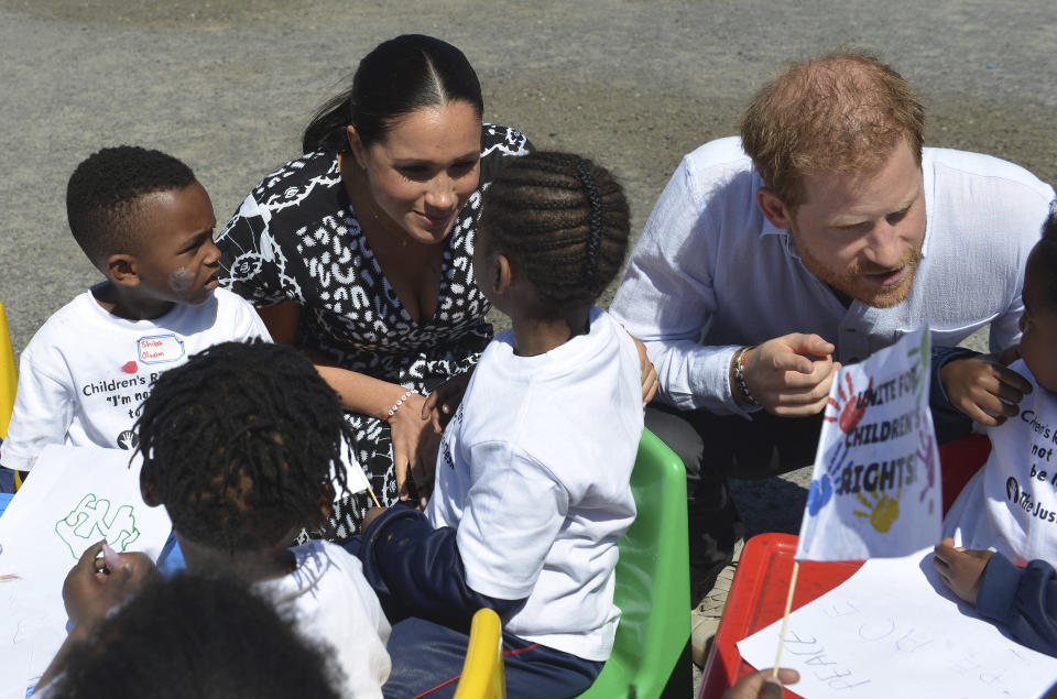 Britain's Prince Harry and Meghan Duchess of Sussex, greet children on their arrival at the Nyanga Methodist Church in Cape Town, South Africa, Monday, Sept, 23, 2019, which houses a project where kids are taught about their rights, self-awareness and safety, and are provided self-defence classes and female empowerment training to young girls in the community. The royal couple are starting their first official tour as a family with their infant son, Archie (Courtney Africa / Africa News Agency via AP, Pool)