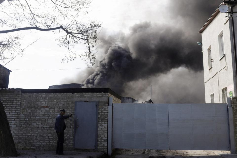 A person rings the bell outside a burning building in Kharkiv on Saturday, following Russian shelling (REUTERS/Ricardo Moraes)