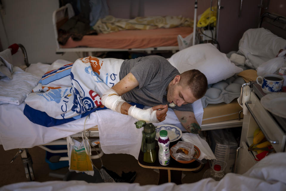 Anton Gladun come como puede en su cama de un hospital de Cherkasy (Ucrania) el 6 de mayo del 2022. Gladun, un médico militar de 22 años, perdió partes de las dos piernas y de un brazo al estallar una mina rusa el 27 de marzo. (AP Photo/Emilio Morenatti)