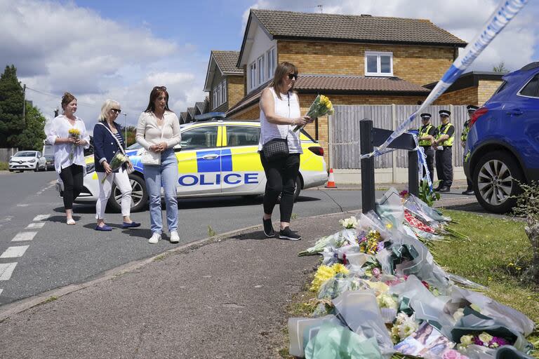 La amiga de la familia Lea Holloway, a la izquierda, llega con otras personas para rendir homenaje tras la muerte de tres mujeres en un ataque a su casa (Jonathan Brady/PA via AP)