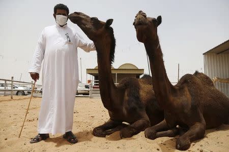 A man wearing a mask poses with camels at a camel market in the village of al-Thamama near Riyadh May 11, 2014. REUTERS/Faisal Al Nasser