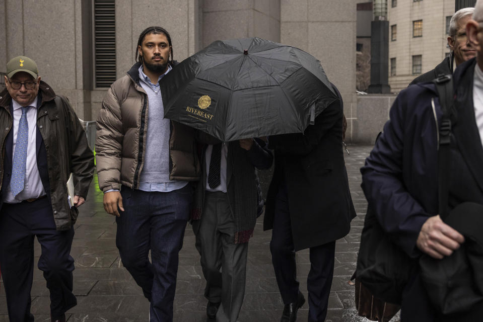 Joe Lewis, center, leaves Manhattan Federal court under cover of an umbrella after pleading guilty to insider trading charges, Wednesday, Jan. 24, 2024, in New York. Lewis, the British billionaire whose family trust owns the Tottenham Hotspur soccer club, pleaded guilty to charges alleging that he fed corporate secrets to romantic partners, personal assistants, friends and his pilots, earning them millions of dollars illegally. (AP Photo/Yuki Iwamura)