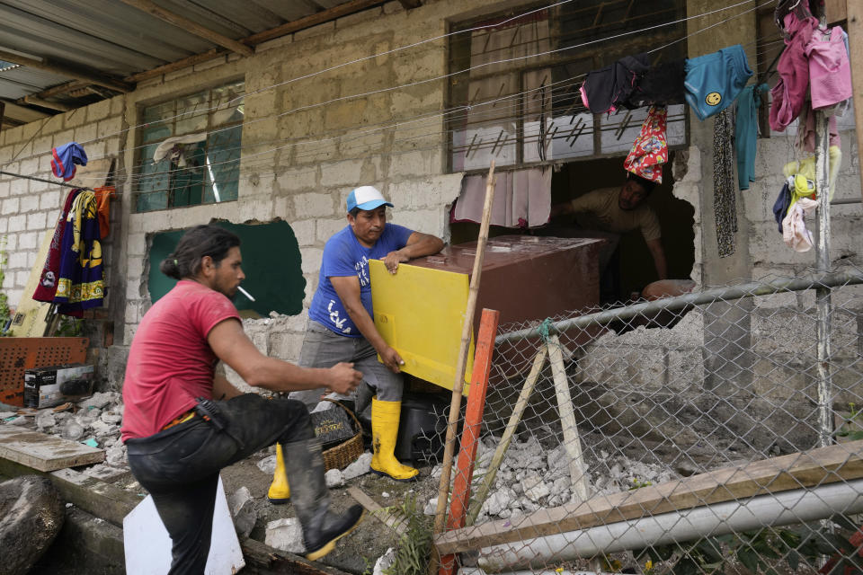 People rescue belongings from their house damaged by a landslide set by heavy rains in El Placer, Ecuador, Monday, June 17, 2024. (AP Photo/Dolores Ochoa)