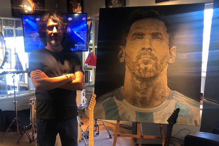 Jorge "Coqui" López pusa junto al retrato que hizo de Lionel Messi, con tierra de su casa natal y de las primeras canchas donde jugó el rosarino.