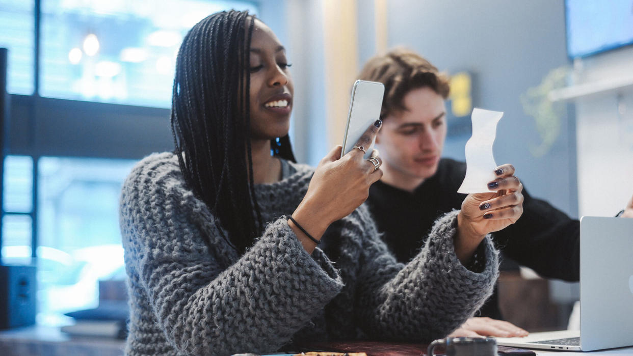 Young woman photographing a receipt in the cafe.