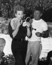 <p>Lucille fixes her lipstick as her makeup artist stands by. The Hollywood beauty was known for her famous red hair, but few know it's not her natural hair color. When she was a 27-year-old aspiring actress, she <a href="https://www.popsugar.co.uk/beauty/Lucille-Ball-Natural-Hair-Colour-46472035" rel="nofollow noopener" target="_blank" data-ylk="slk:dyed it red;elm:context_link;itc:0;sec:content-canvas" class="link ">dyed it red</a> to separate herself from her competition.</p>