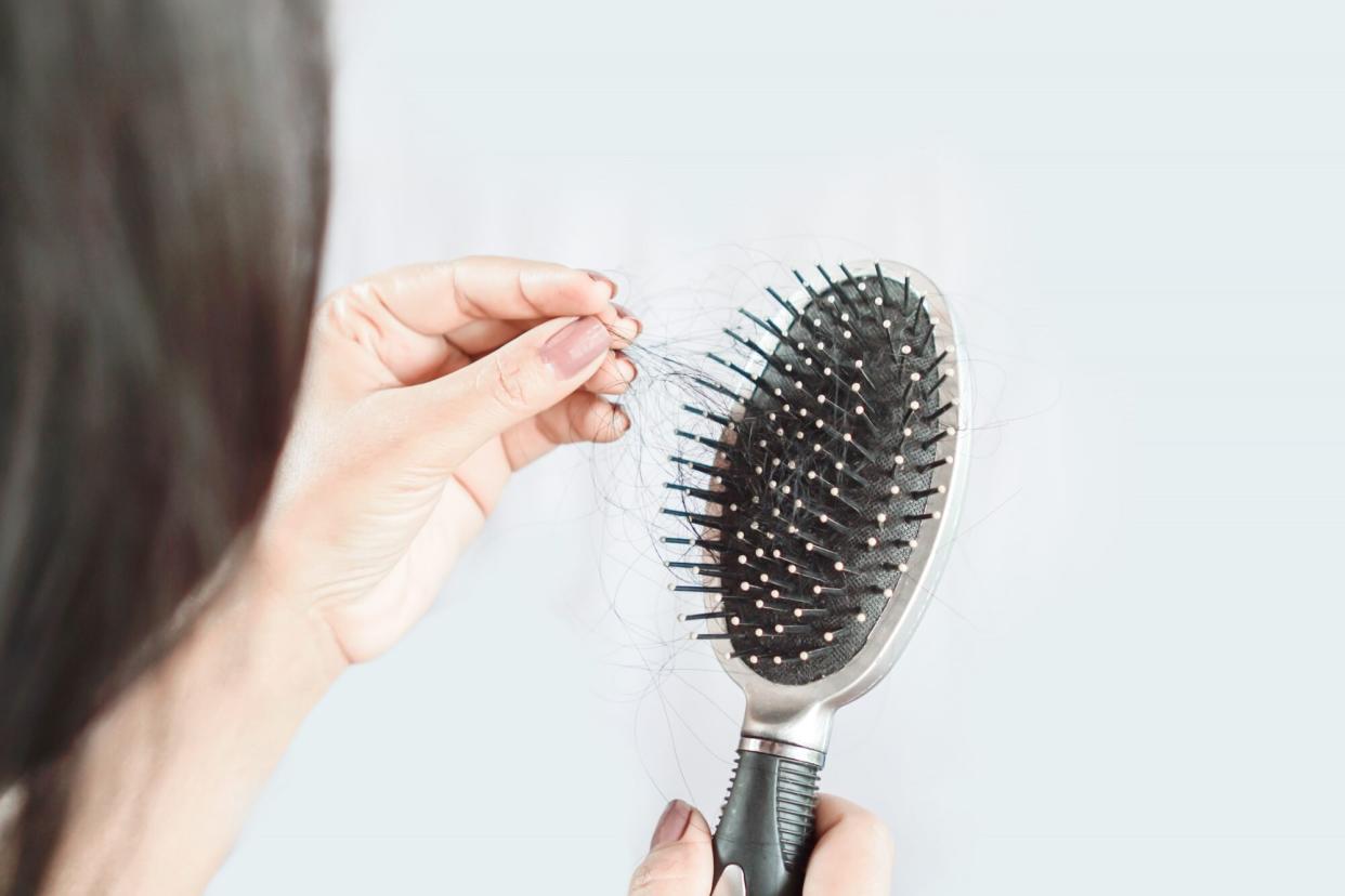 woman pulling hair out of brush