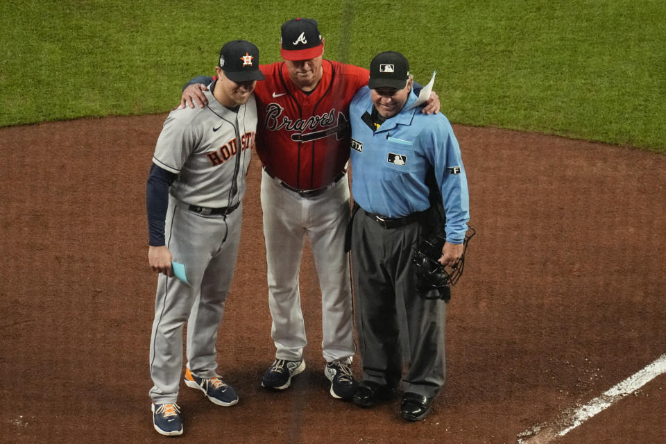 Atlanta Braves manager Brian Snitker, center, poses with his son Houston Astros hitting coach Troy Snitker and home plate umpire Alfonso Marquez before Game 3 of baseball's World Series between the Houston Astros and the Atlanta Braves Friday, Oct. 29, 2021, in Atlanta. (AP Photo/Ashley Landis)