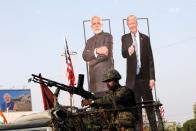 An Indian army soldier sits atop an armoured vehicle next to cutouts of India's Prime Minister Narendra Modi and U.S. President Donald Trump along a road, ahead of Trump's visit, in Ahmedabad
