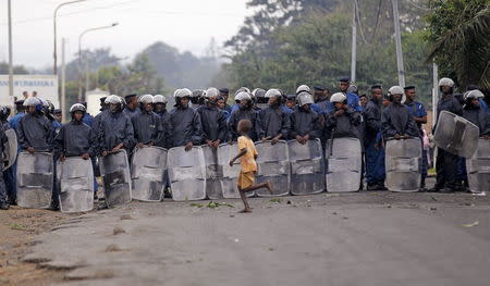 A child runs across a line of riot policemen standing in a formation as protestors gather and chant slogans in Bujumbura, Burundi April 30, 2015. REUTERS/Thomas Mukoya