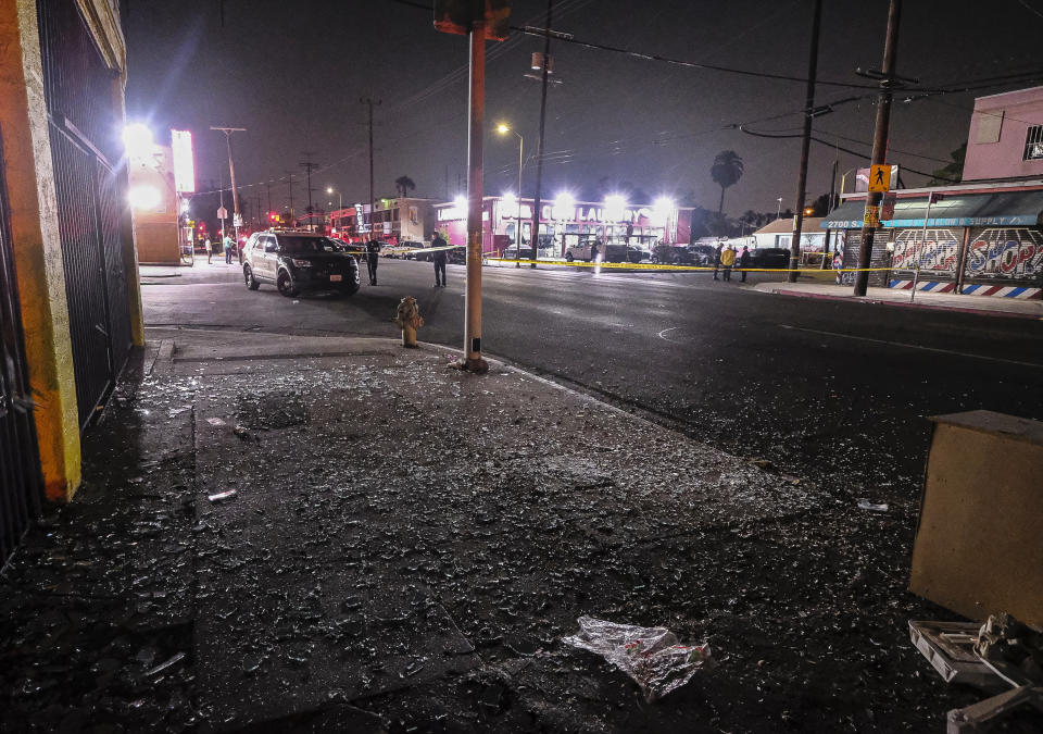 Broken glass sits on a sidewalk and street after a fireworks explosion in Los Angeles on Wednesday, June 30, 2021. A cache of illegal fireworks seized at a South Los Angeles home exploded, damaging nearby homes and cars and causing injuries, authorities said. (AP Photo/Ringo H.W. Chiu)