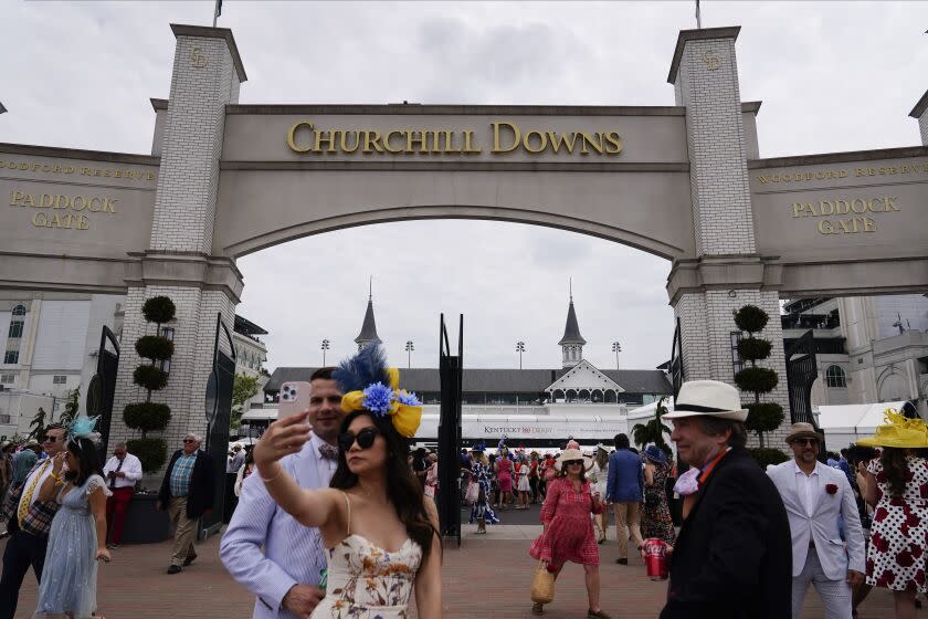 People walk on the grounds of Churchill Downs before the 149th running of the Kentucky Derby